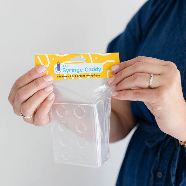 Adult holding The Syringe Caddy, designed for storing 1ml to 10ml medicine syringes.