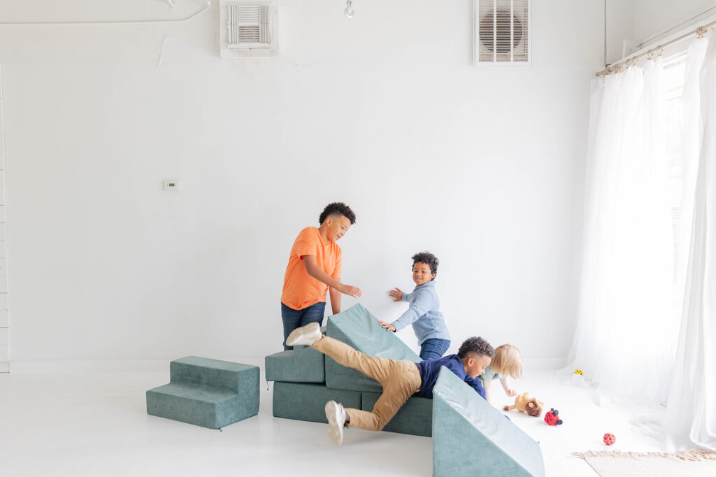 Children playing with cushioned climbing blocks in a bright playroom. Family Health is of great importance.